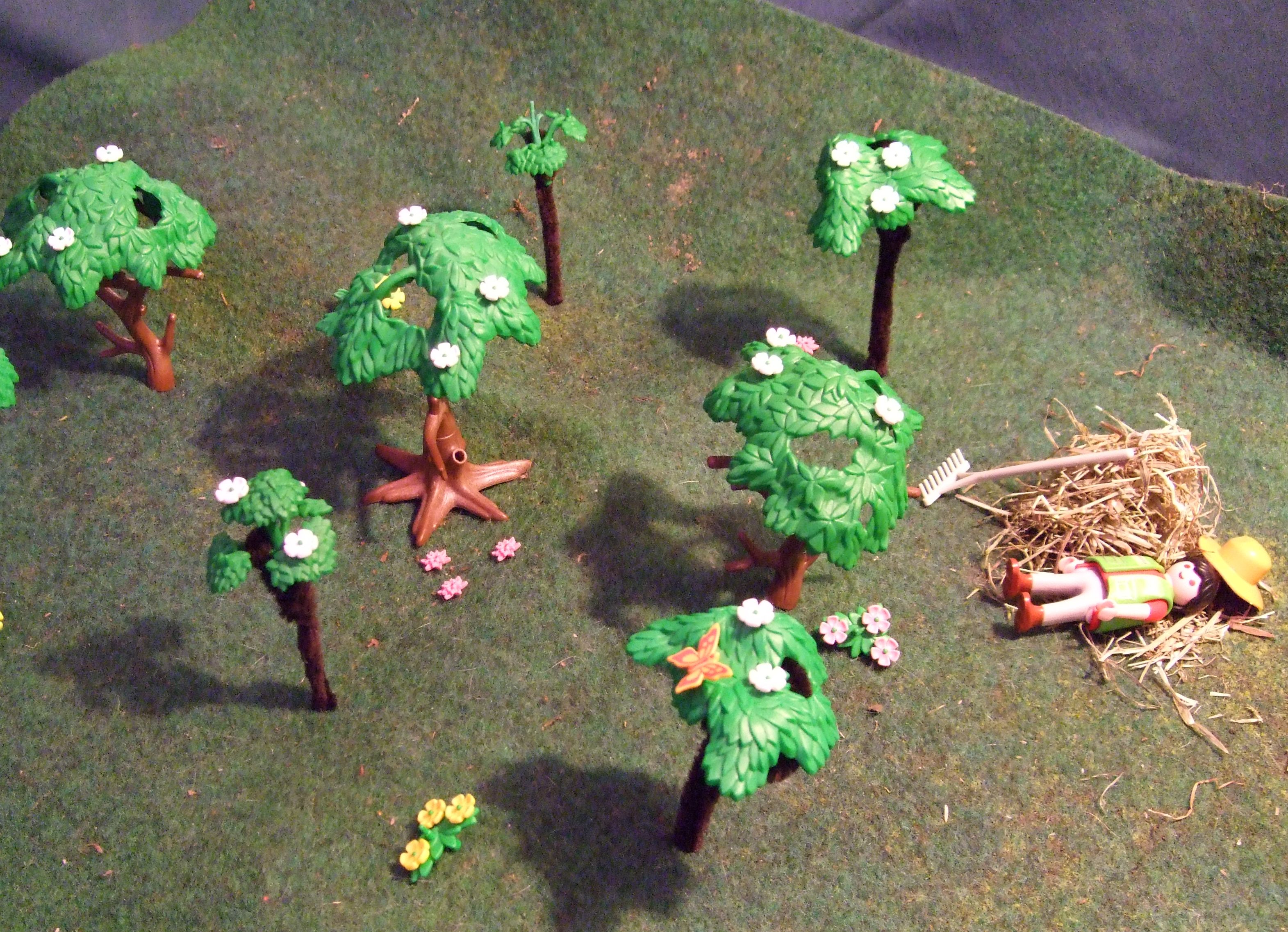 Aus Playmobilfiguren wurde eine Obstwiese dargestellt. Es sind 7 Bäume und ein liegender Gärtner auf einer Wiese zu sehen