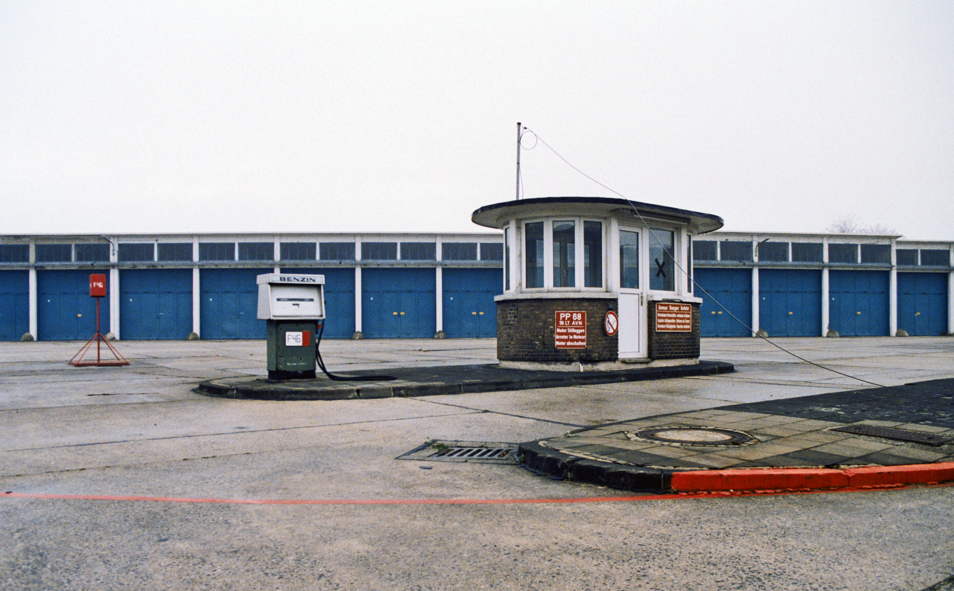 Historisches kleines Tankstellengebäude mit einer alten Zapfsäule vor blau weißen Garagen