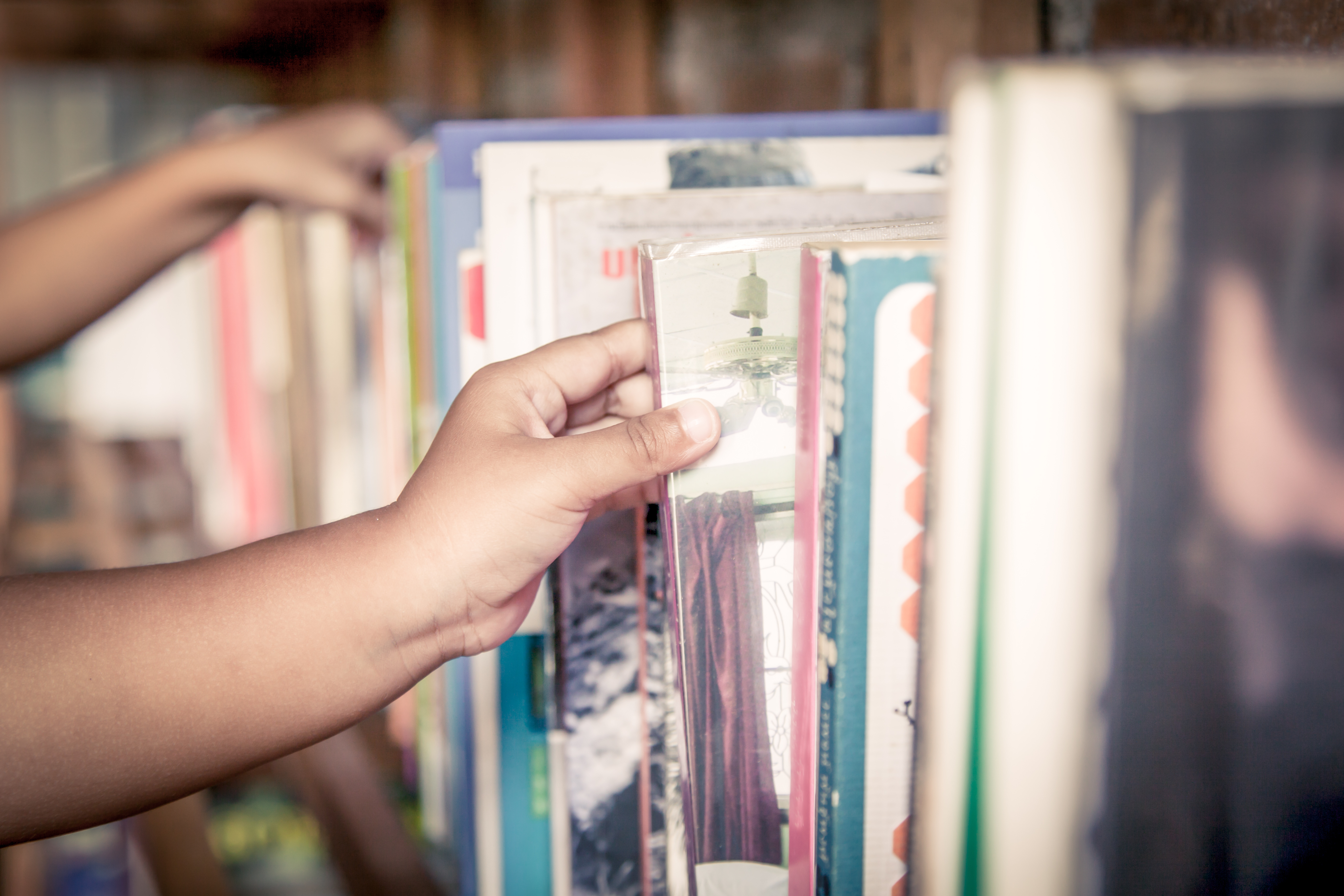 Eine Hand zieht ein Buch aus einem Bücherregal