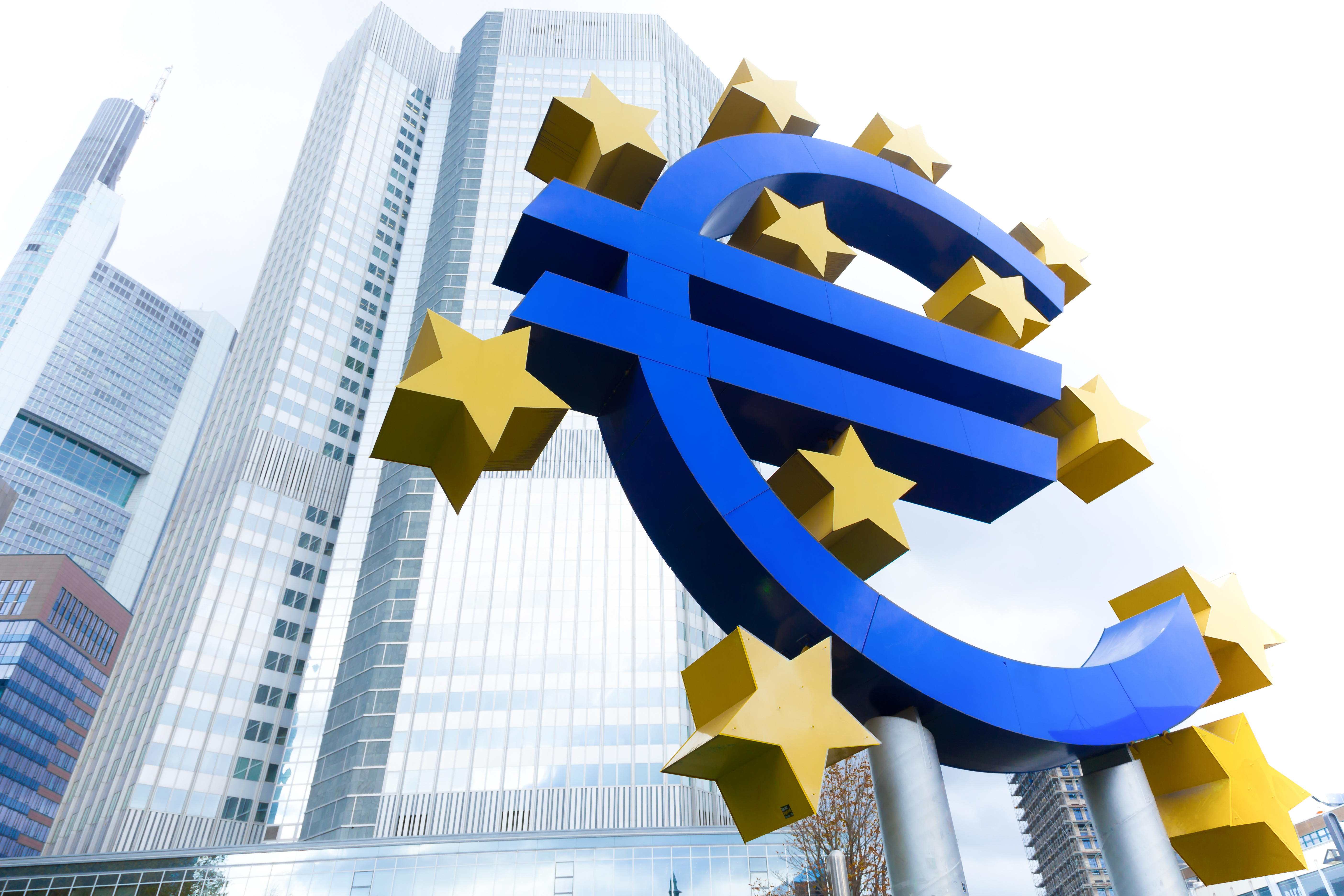 Das Euro Symbol umgeben von Sternen vor einem Hochhauskomplex