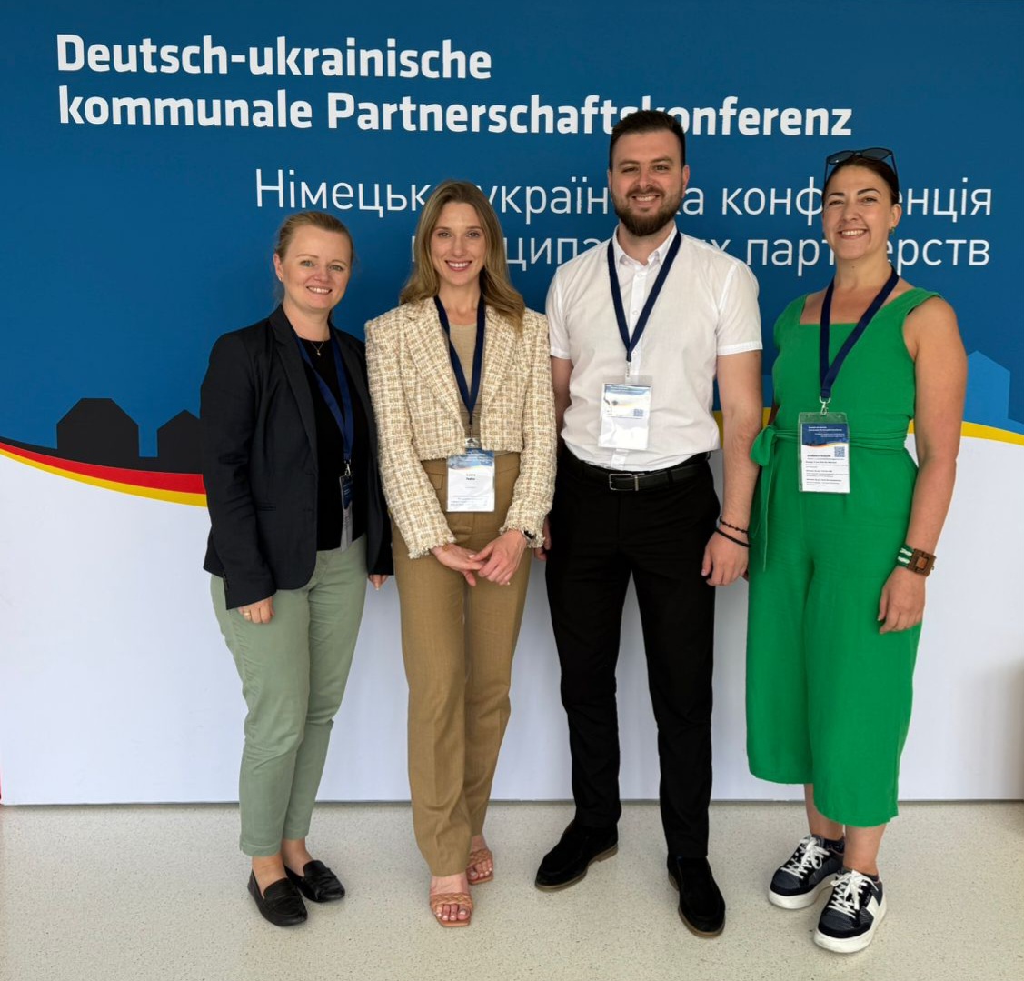 Auf dem Bild befinden sich 4 Personen, die vor einem Banner stehen, auf dem in deutsch und ukrainisch geschrieben steht: Deutsch-ukrainische kommunale Partnerschaftskonferenz