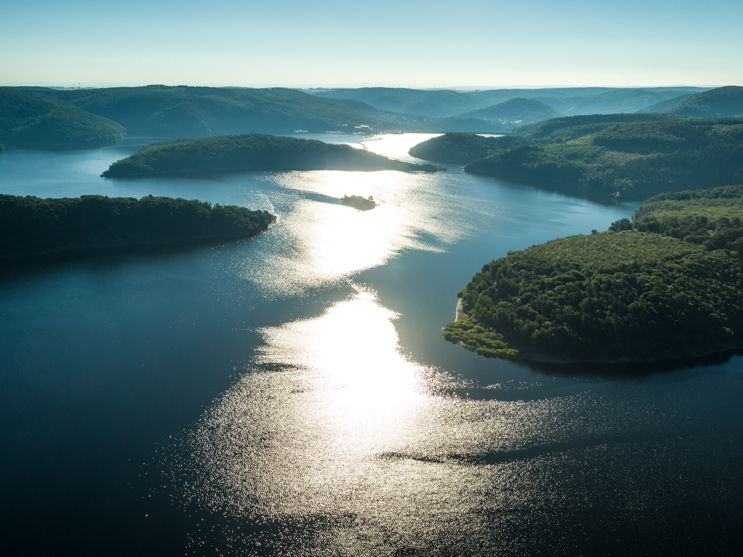 Seenlandschaft mit Inseln. Im See spiegelt sich die Sonne