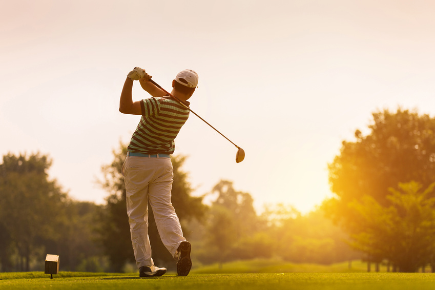 Ein Mann, der im Sonnenuntergang Golf spielt