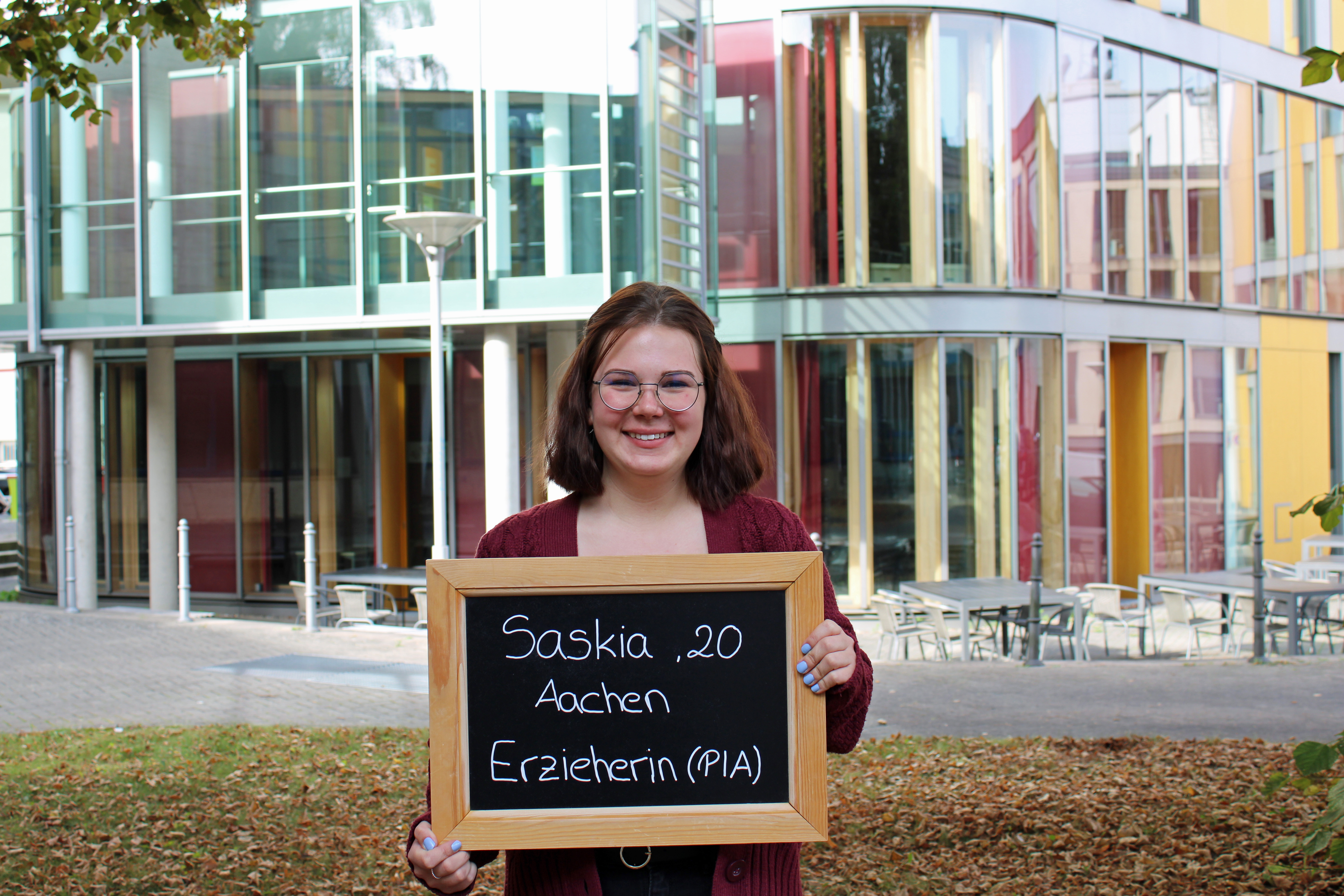 Saskia hält eine Tafel mit ihrem Namen, Alter und ihrem Ausbildungsberuf