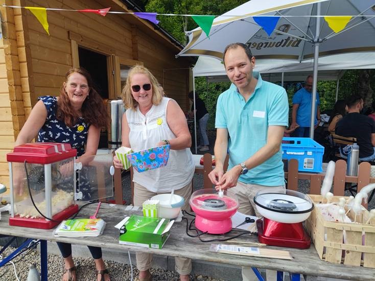 Zwei Frauen und ein Mann an einer Zuckerwattemaschine.