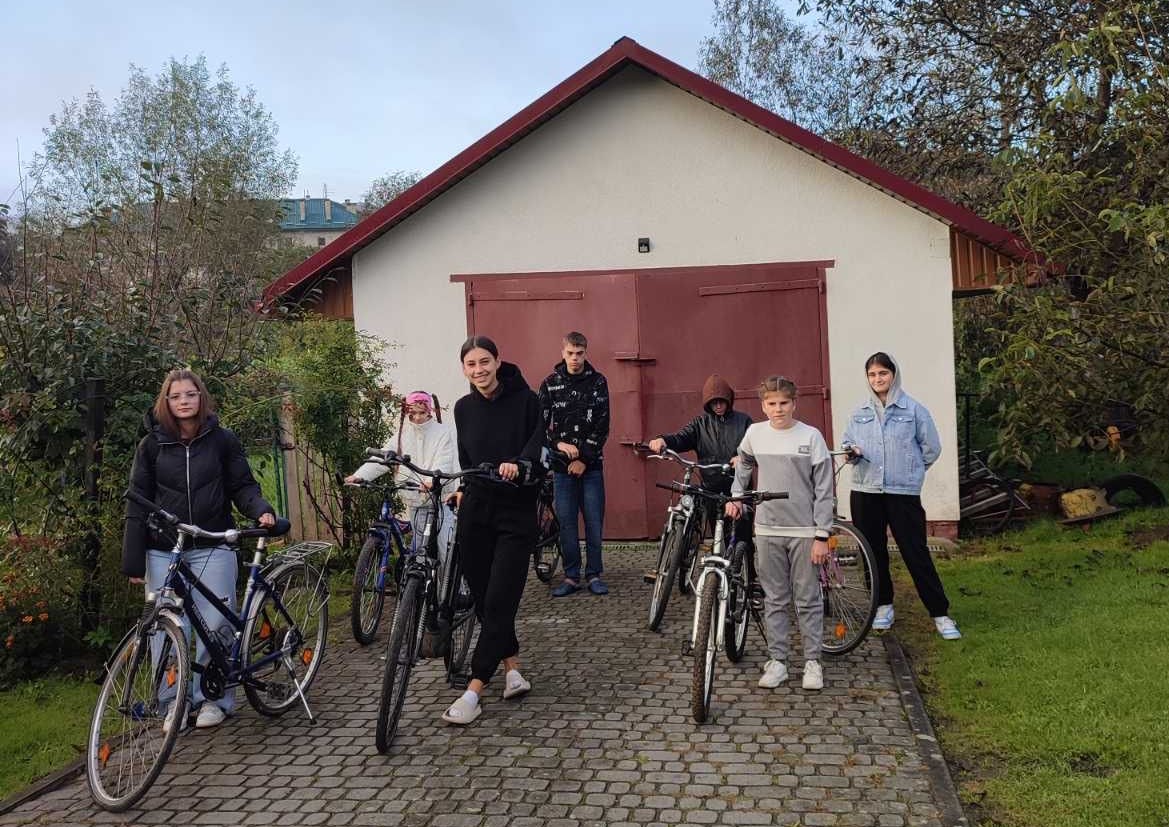 Junge Menschen stehen mit Fahrrädern vor einer Garage.