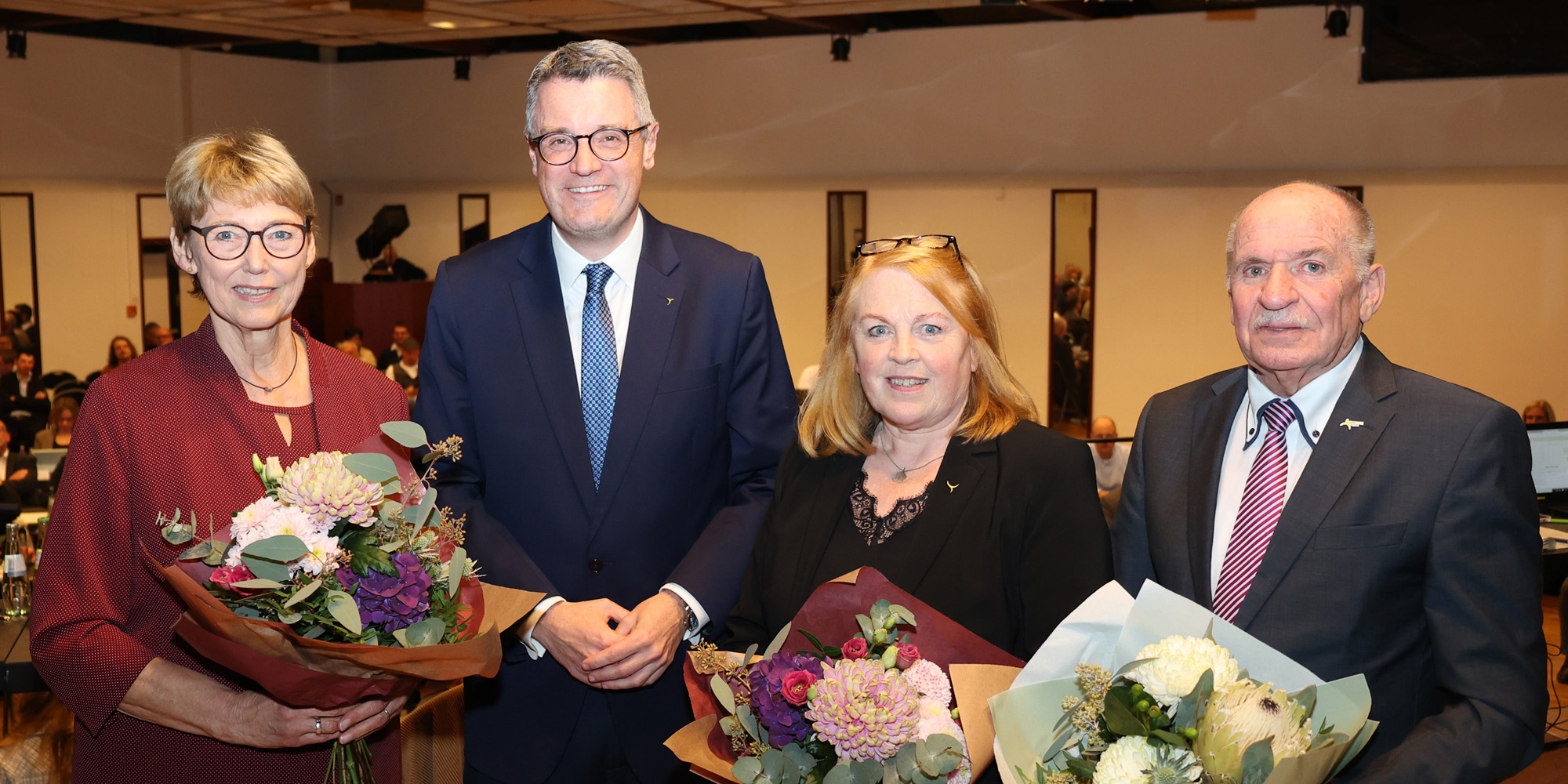Zwei Frauen und zwei Männer mit Blumensträußen.
