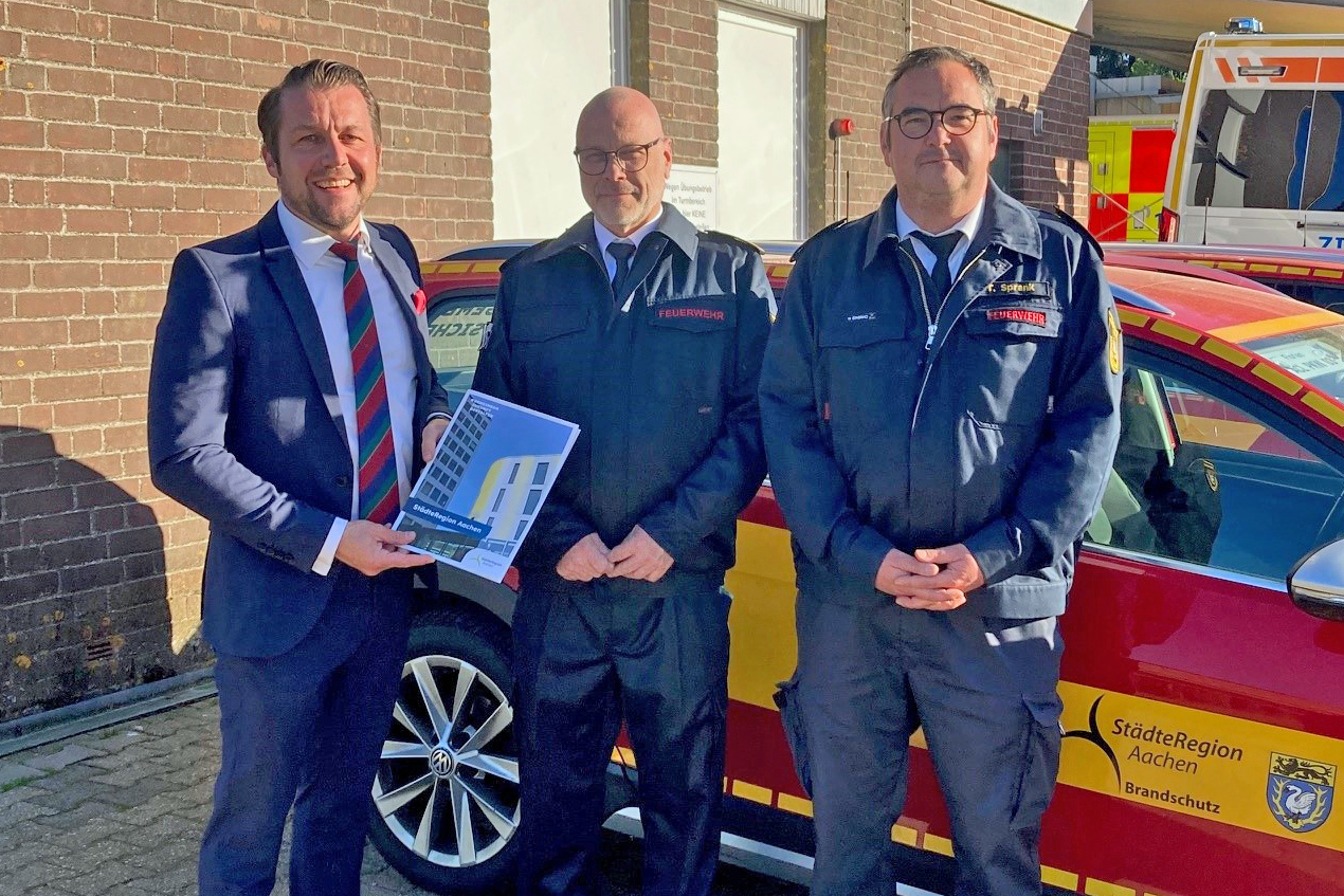 Drei Männer vor einem Feuerwehrwagen
