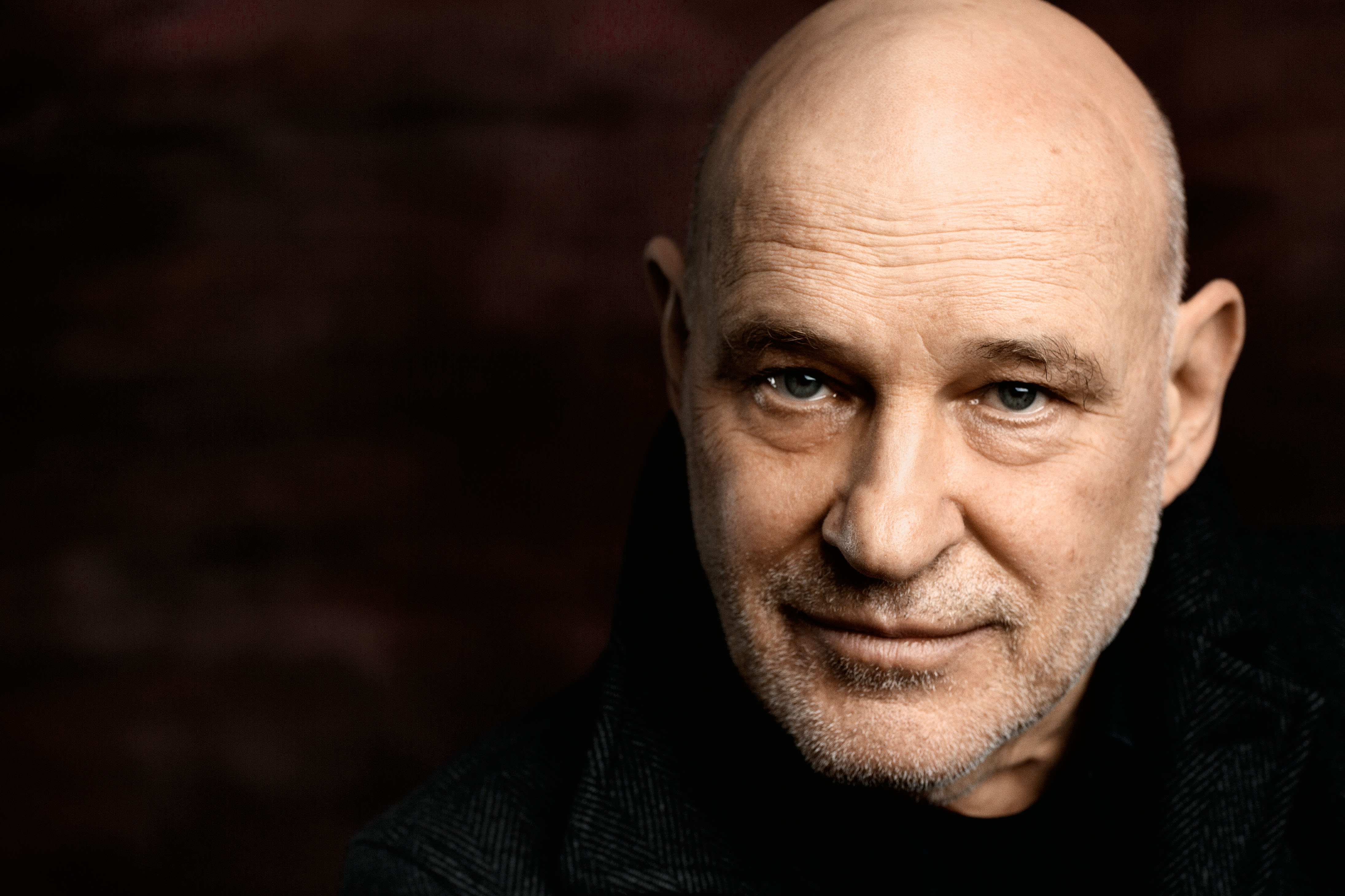 Porträt des Schauspielers Christian Redl vor schwarzem Hintergrund